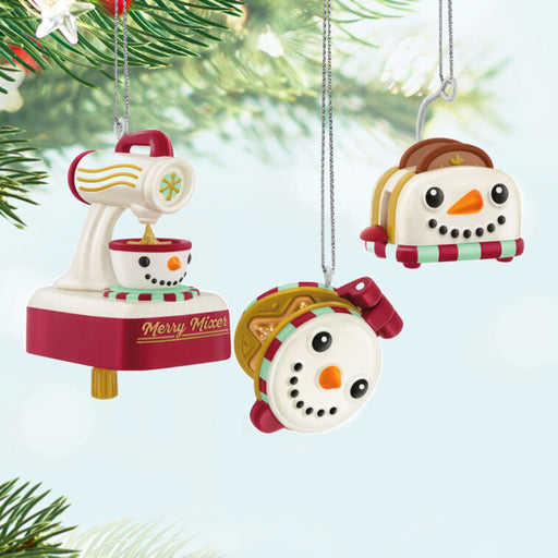 Three Christmas cooking ornaments  with snowman faces, a mixer, a toaster and a waffle maker ornament on  a Christmas tree.