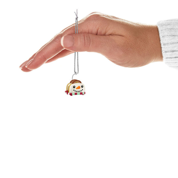 Hand holding a snowman themed toaster ornament  with a white background