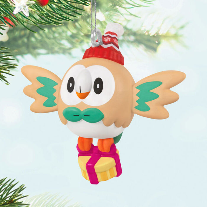 Mini Christmas ornament shaped like a Pokémon cartoon owl with a red hat and green bow tie, hanging from a tree.