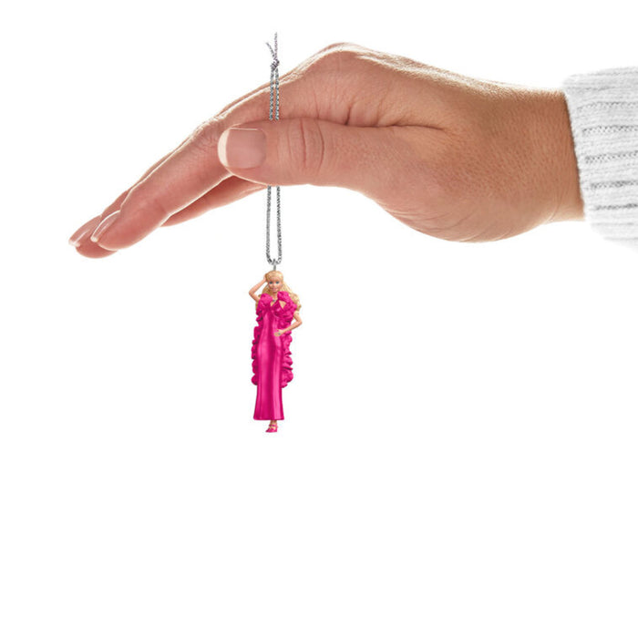 Hand holding a Mini Hallmark Keepsake Barbie  ornaments with the pink dressed Barbie on a white background
