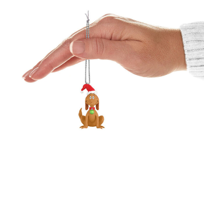 Hand holding a Mini ornament of Max the Dog from Grinch with a Santa hat and green ornament in his collar  on a white background on a white background. 