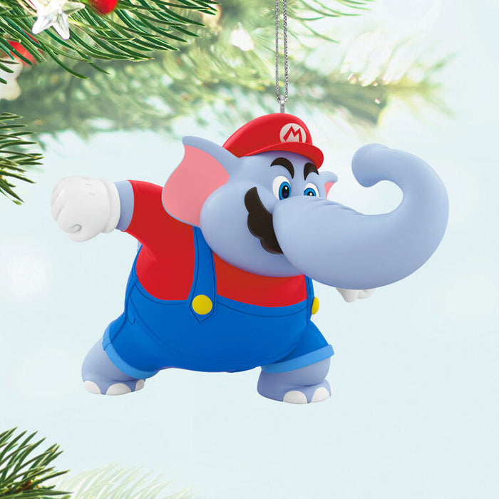 Cartoon elephant character ornament from Mario Nintendo game ,wearing a red cap with a white 'M' and blue overalls hanging from a Christmas tree .