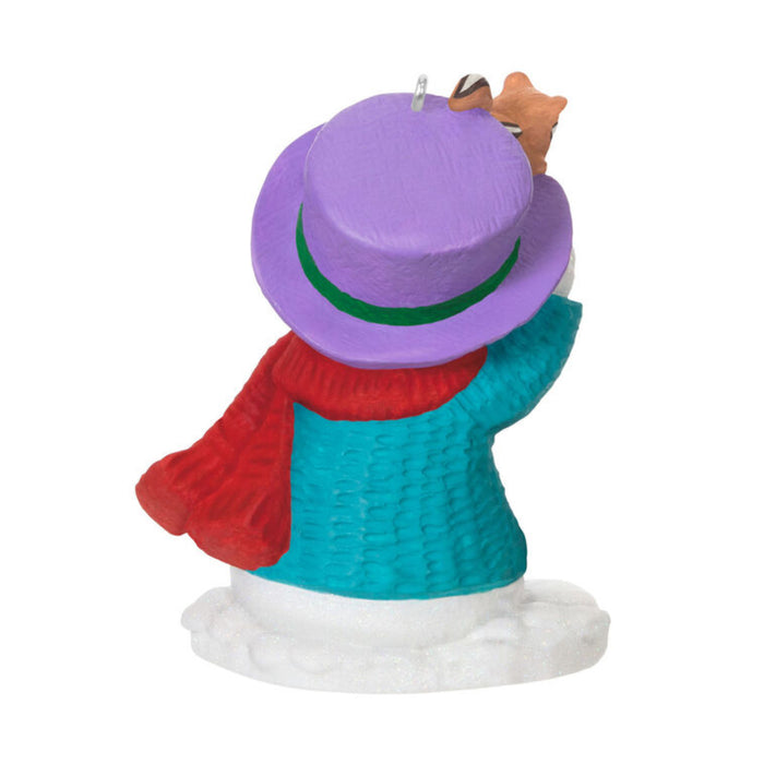 backside of Christmas ornament of a snowman with a purple hat and blue sweater, pointing at his buddy chipmunk , on a white background. 