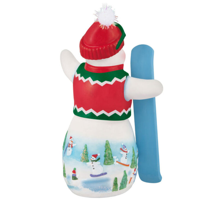  Backside of the 2025 Hallmark snowman ornament with goggles, hat, and sweater vest with a  snow board on white background; part of the Snowtop Lodge series.