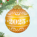 Decorative warm yellow Christmas glass ball ornament with year '2025', on a tree branch