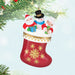 Christmas ornament with Santa, snowman, and woman in a stocking  hanging from a tree. 