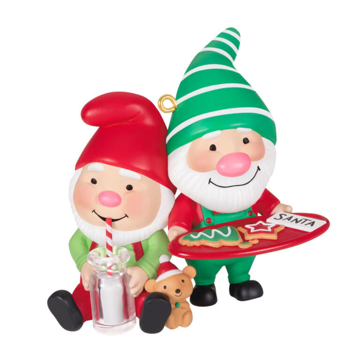 Christmas ornament featuring two elves, one holding a tray with cookies and the other with a glass of milk on a white background 
