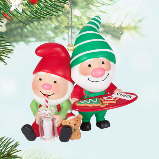 Christmas ornament featuring two elves, one holding a tray with cookies and the other with a glass of milk, Hanging on a christmas tree