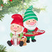 Christmas ornament featuring two elves, one holding a tray with cookies and the other with a glass of milk, Hanging on a christmas tree