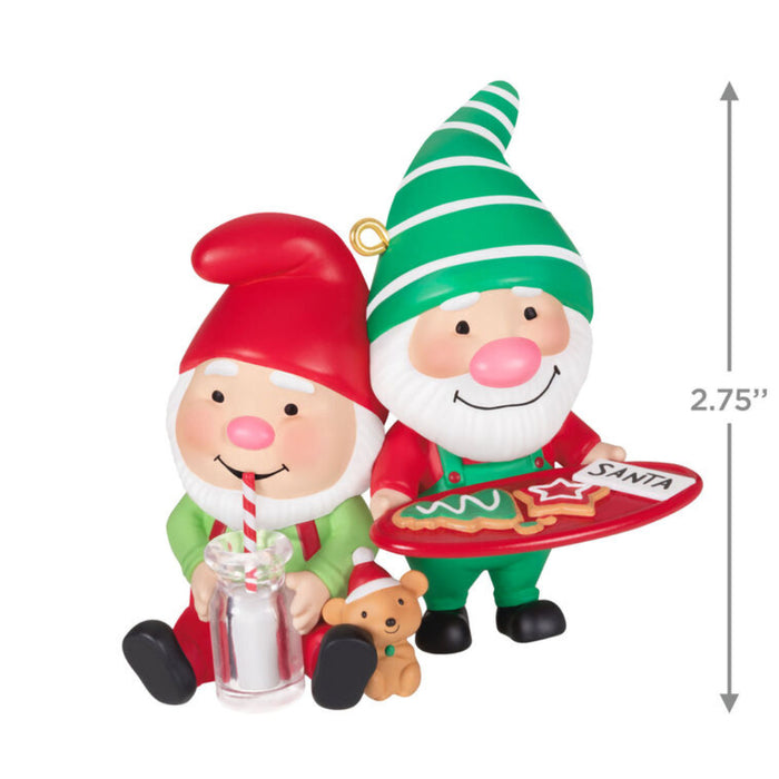 Christmas ornament featuring two elves, one holding a tray with cookies and the other with a glass of mill with a white background with product dimensions.