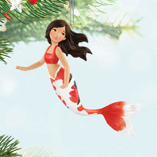 Mermaid ornament with red and white tail hanging from a tree.