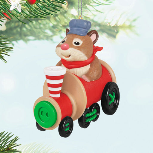 Decorative ornament of a hamster on a toy train made from buttons hanging from a tree. 