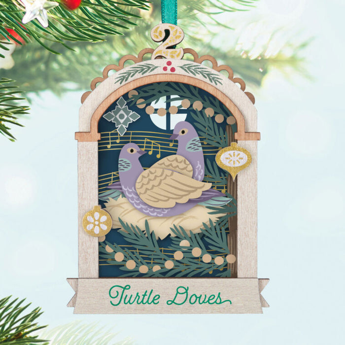 Decorative Christmas ornament with a turtle dove and musical notes hanging on a tree branch.