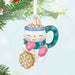 Decorative Christmas Snowman Mug ornament with scarf, and cookie, hanging from a tree.