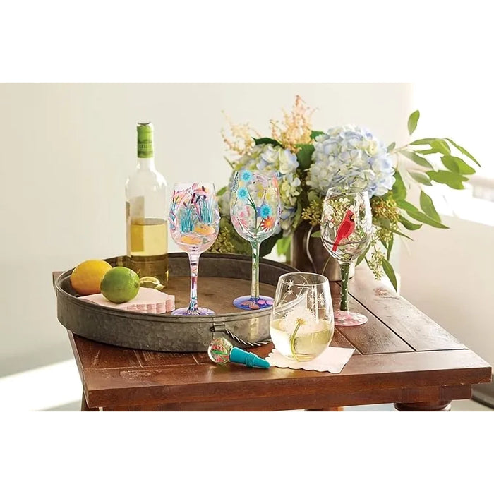 Wine glasses with floral designs on a wooden tray with a bottle of wine and fruit.