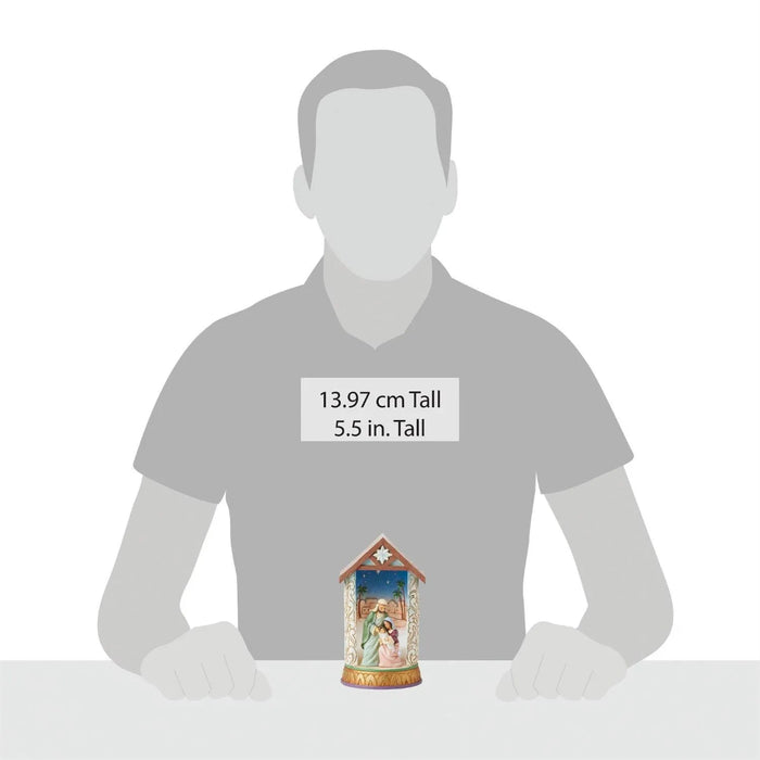 Small  Christmas nativity religious figurine on a white surface with a person's torso in the background for sizing 