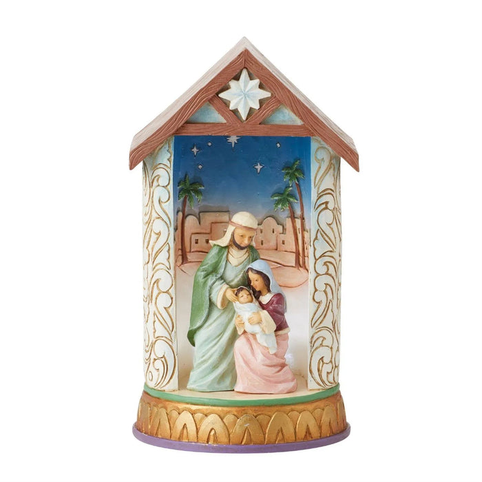 Decorative Jim Shore Figurine nativity scene in a house-shaped container with a star on top light on .