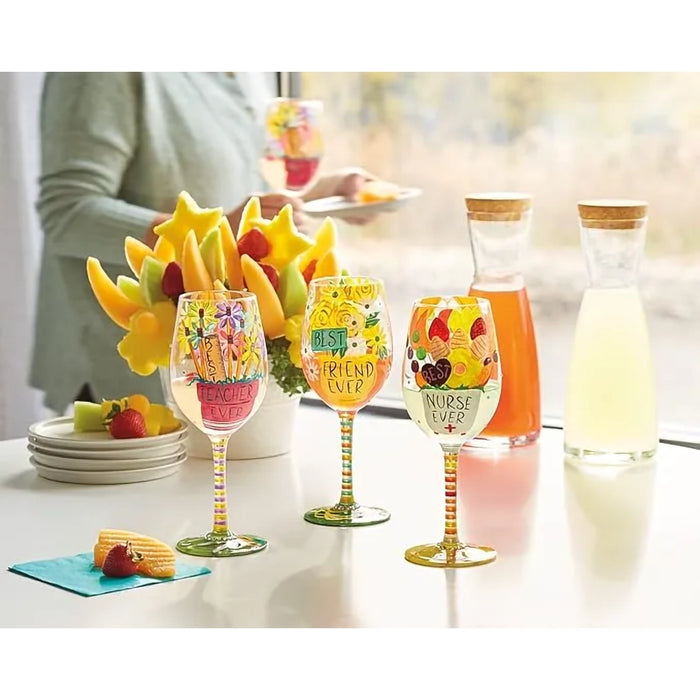 Decorative wine glasses with fruit designs on a table with drinks and fruit.