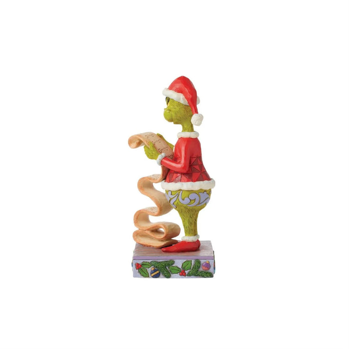 Right side view of  Jim Shore Grinch figurine in a red outfit and Santa hat holding a list, on a white background