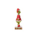 Left side view of Jim Shore Grinch figurine in red patchwork Santa suit, showing detailed hand-painted design on stage on a white background."