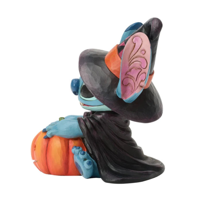 Stitch dressed as a witch standing beside a jack-o-lantern in a playful Halloween figurine.