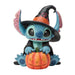 Stitch dressed as a witch standing beside a jack-o-lantern in a playful Halloween figurine.