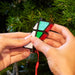 Small Rubik's Cube-like puzzle held by hands with a Christmas tree background
