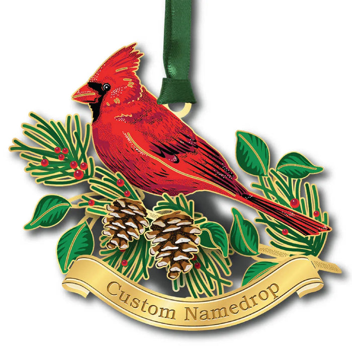 Christmas ornament with a red cardinal, green leaves, and pine cones on a white background.