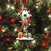 Decorative Christmas ornament with a birdhouse, birds, and presents on a tree.