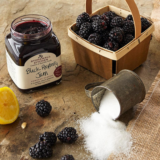 "Open jar of Stonewall Kitchen Black Raspberry Jam with a basket of fresh black raspberries, lemon wedge, and sugar on a rustic table."