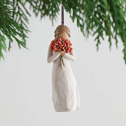 "Willow Tree Surrounded by Love ornament featuring a faceless figurine holding a bouquet of red poppies, hanging from a Christmas tree branch – hand-painted resin collectible by Susan Lordi"