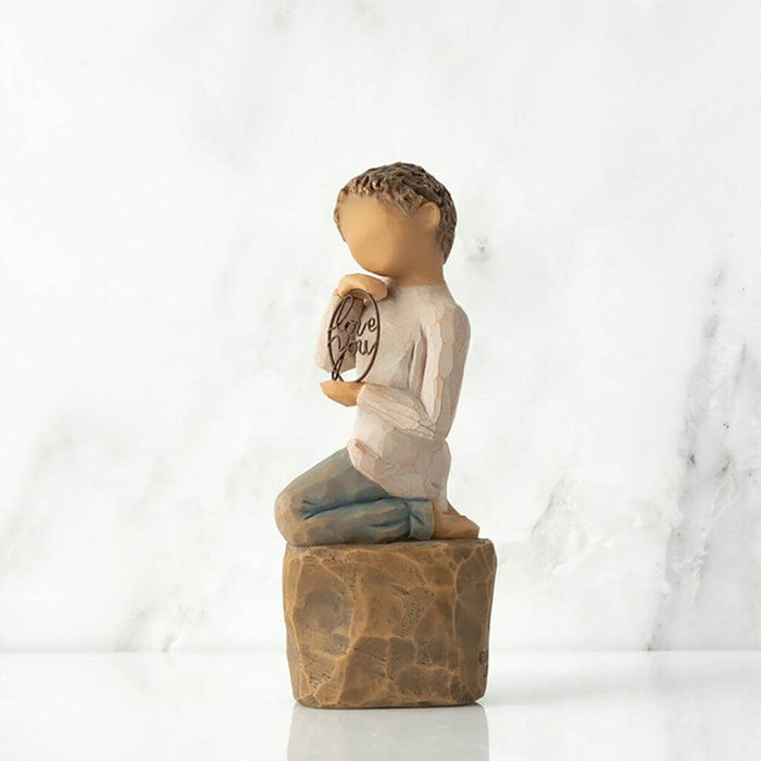 "Willow Tree Love You Too figurine – hand-painted sculpture of a boy with lighter skin kneeling and holding a wire sign that says 'love you'."