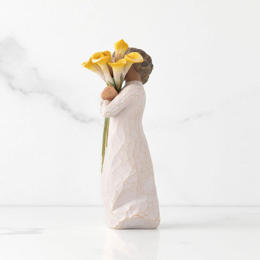 "Willow Tree With Gratitude figurine – hand-painted resin sculpture of a woman with darker skin tone holding a bouquet of yellow calla lilies in appreciation"