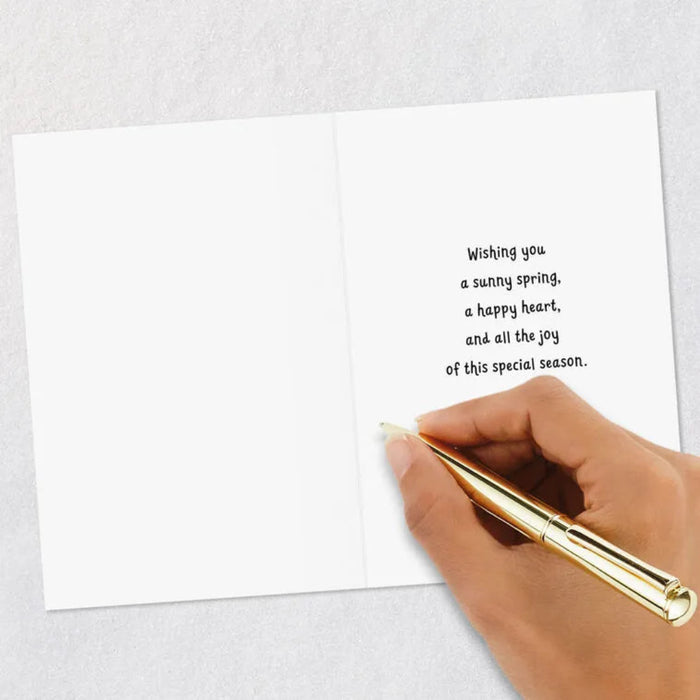 Hand holding a gold pen over a white card with a message on a light gray background