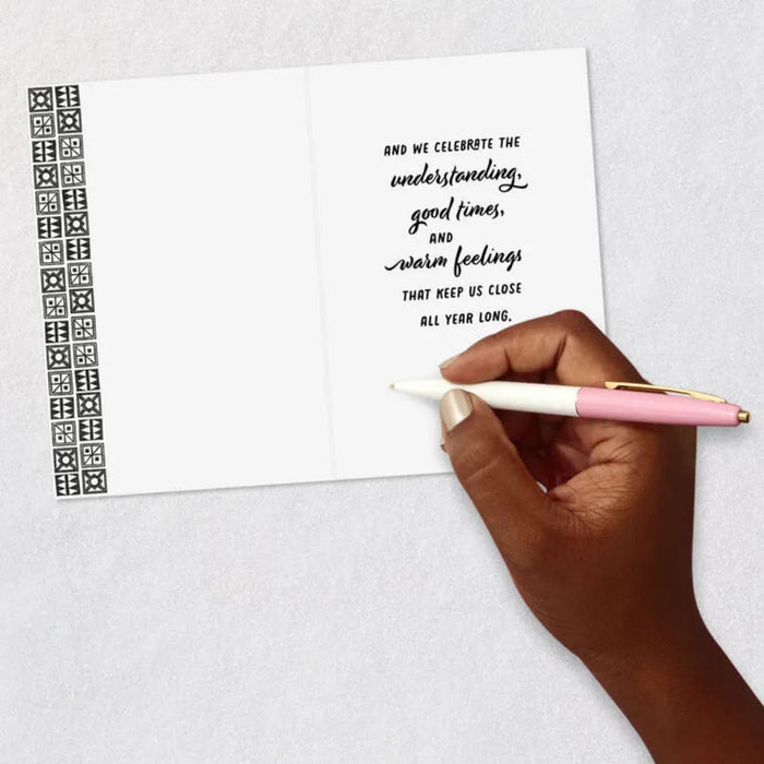 Handwritten message on a card with a pen held by a hand, on a light gray background