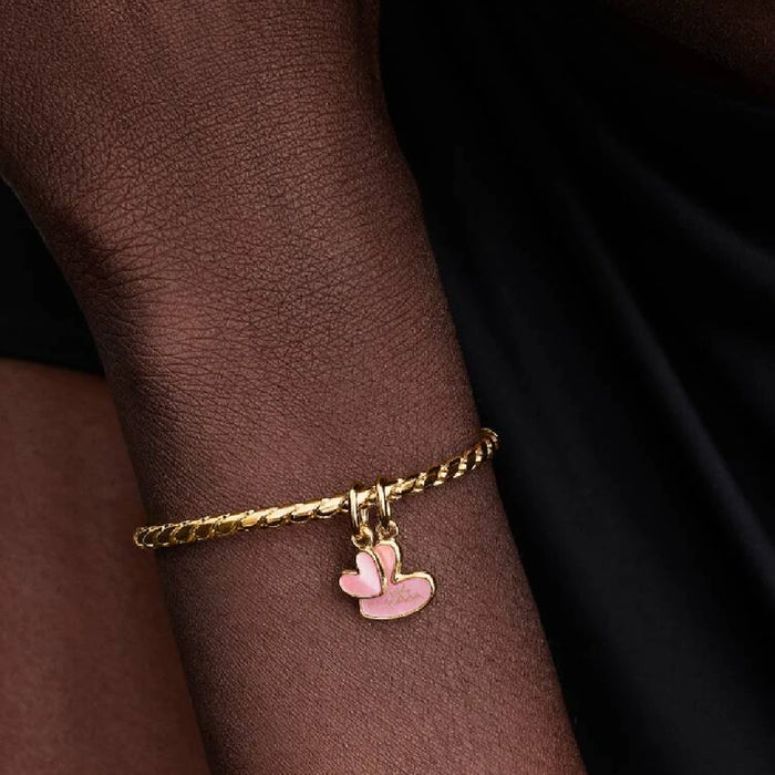 A heart-shaped charm coated in pink enamel, offering a stylish and eye-catching accessory.