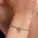 Close‑up of sterling silver and 14k gold‑plated Tiana Water Lily charm on a wrist