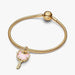 Gold bracelet with a pink heart charm on a white background