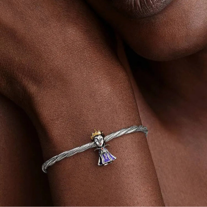 Close-up of a hand wearing a silver bracelet with a charm, against a neutral background.