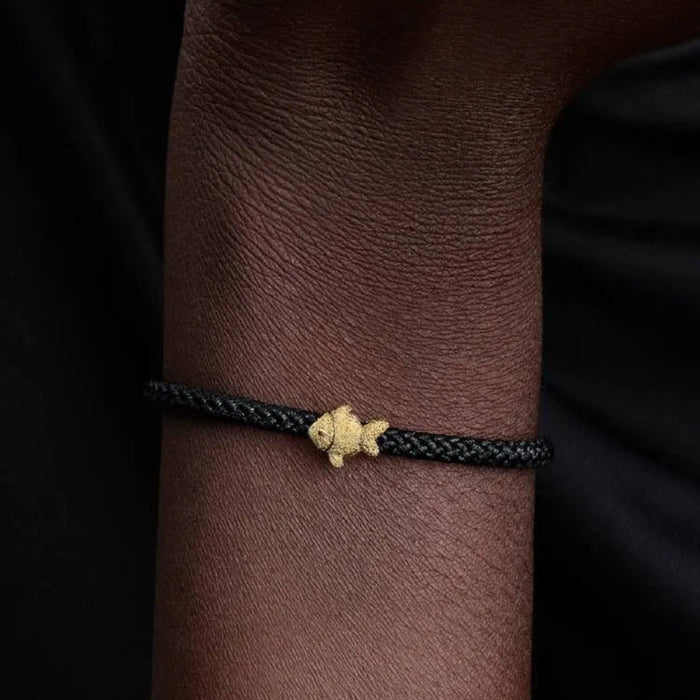 Bracelet with a gold clasp on a wrist against a dark background