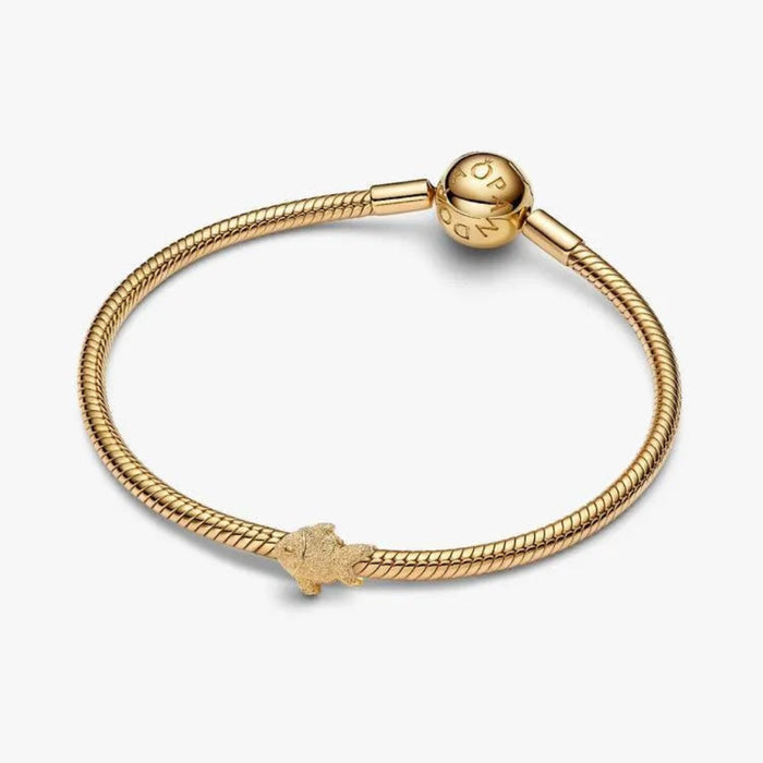 Gold bracelet with a small charm on a white background