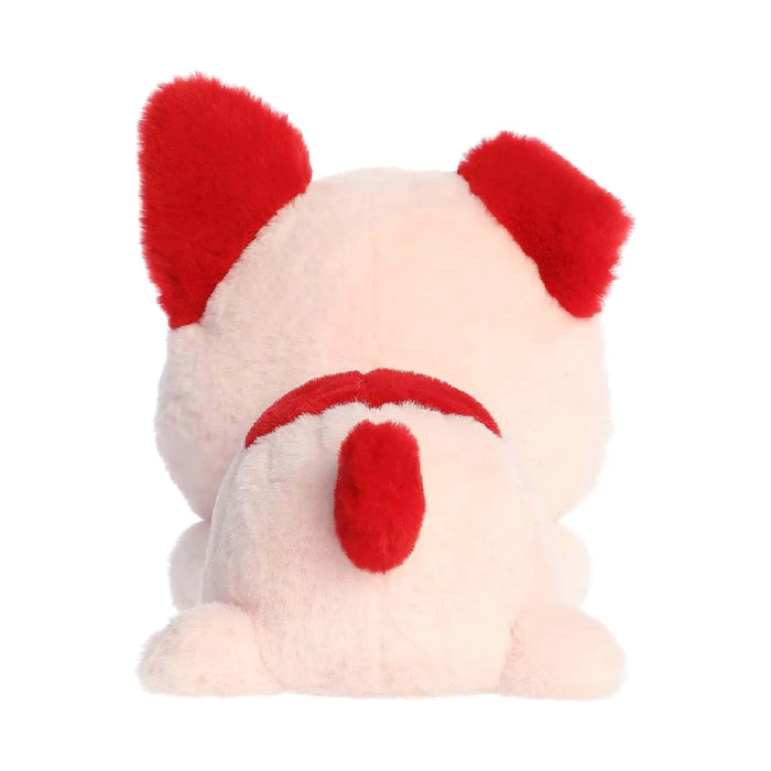 A pink stuffed creature with a vibrant red collar, placed on a plain backdrop.
