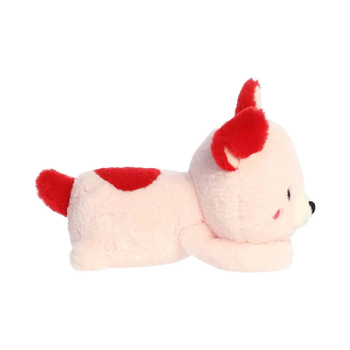A cute pink stuffed animal adorned with a red collar, displayed in a cozy setting.