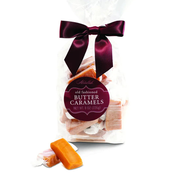 Packaged old-fashioned butter caramels with a purple bow and label on a white background 8oz, on a white background