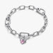 Close‑up of winged heart charm featuring pink crystal and heart cut‑out on a chain