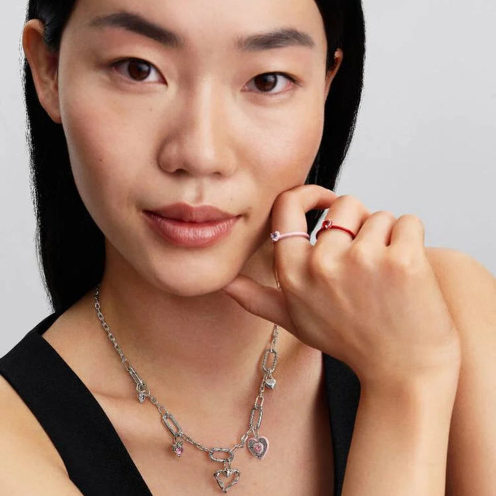 Close‑up of a necklace featuring the polished asymmetric heart charm alongside coordinating charms