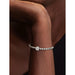 Close-up of a sterling silver bracelet on a model’s wrist featuring the Pandora Textured Paw Mini Charm with a sparkling paw print design.