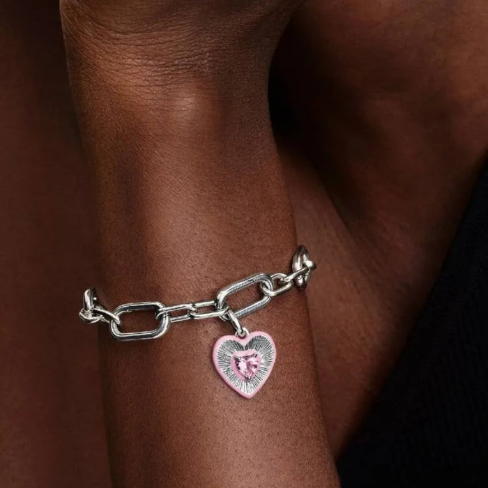 Silver chain bracelet with a heart-shaped charm on a wrist.