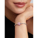 Close-up of a woman's arm wearing a silver bracelet with a pink charm