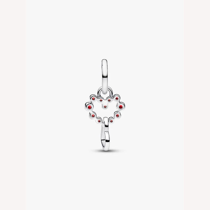 Silver heart charm with red stones on a light background